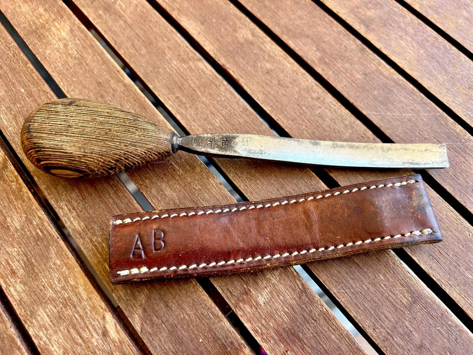 Knife with wooden handle and leather sheath on a wooden table