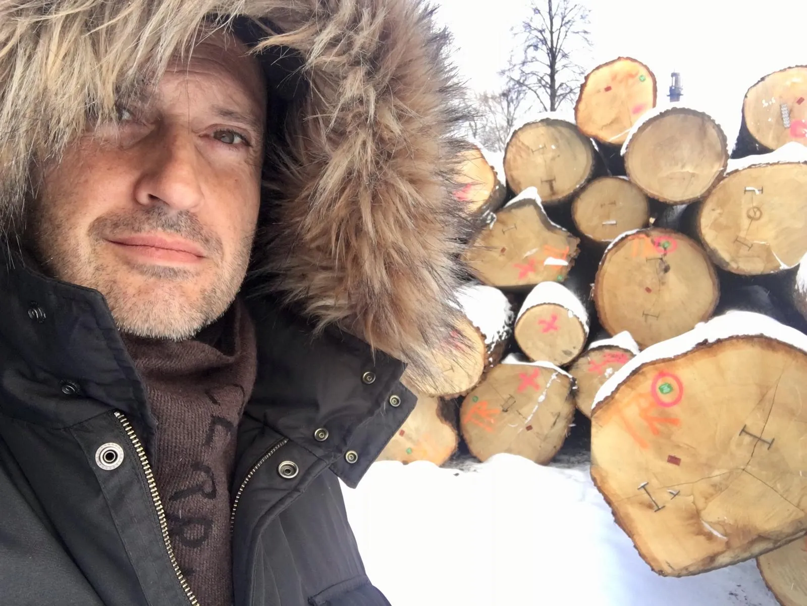 Portrait in winter clothing beside a pile of logs